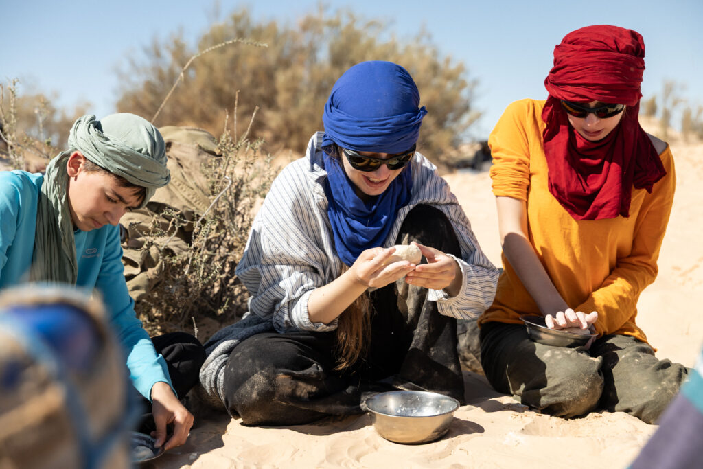 Trois participants faisant du pain. Ils malaxent la pâte encore cru dans un saladier en inox ou à la main