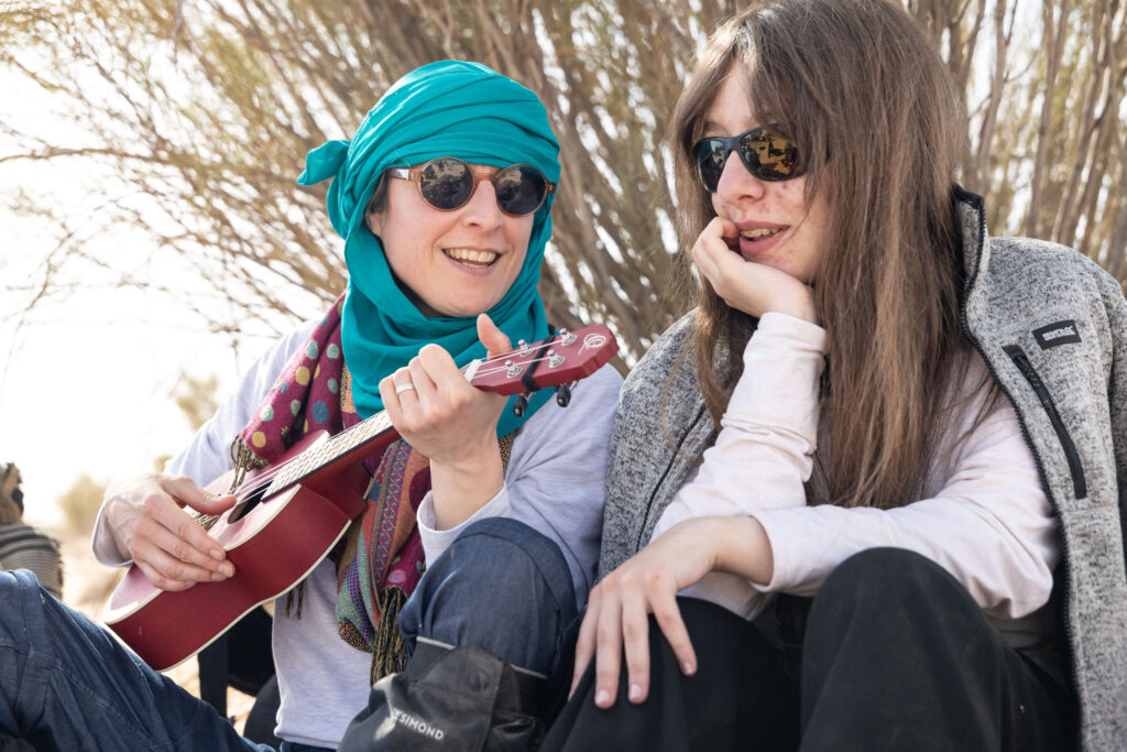 Deux participants femme discutant dont une tient une guitare à deux mains