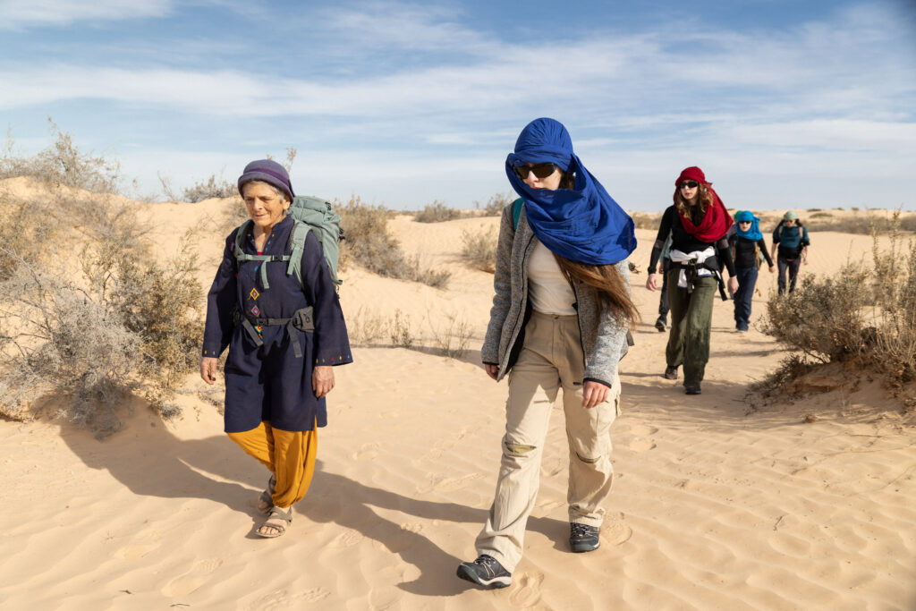 Début de la caravane avec Marie-Hélène, la présidente de l'association, et des participants marchant dans le désert