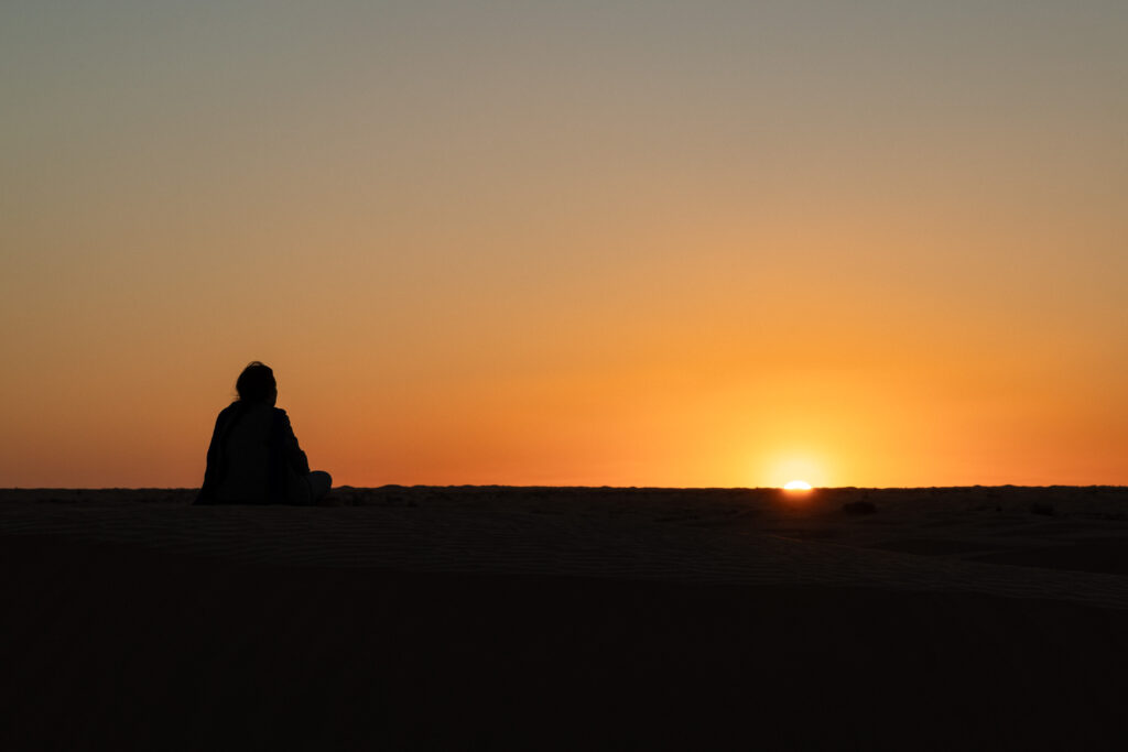 Coucher de soleil avec la silhouette d'un participant de dos. On devine qu'il regarde le crépuscule