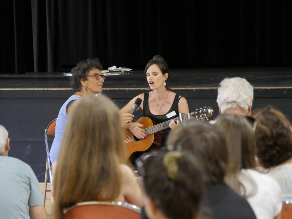 Marie-Cathy, participante au tout premier voyage, nous chante une chanson de son répertoire. Elle est accompagnée de Anne, l'animatrice de la journée.